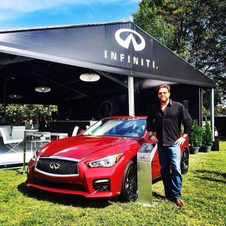 scott standing beside a car infront of the Infiiniti banner 